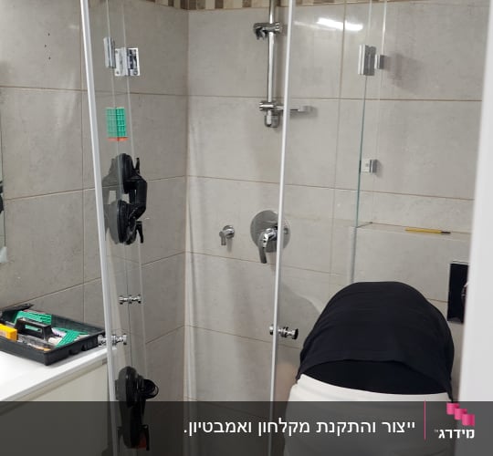 התקנת דלת זכוכית במקלחת עם אריחים אפורים